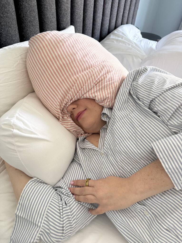 A woman, sleeping on her side, with a Sleep Crown wrapped around her face.